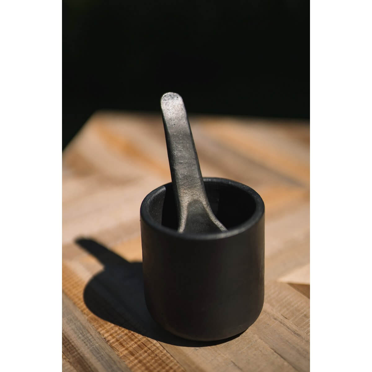 De verbrande beker zwart servies met lepel, perfect voor sauzen en gerechten, deel van de Burned-collectie voor foodlovers.