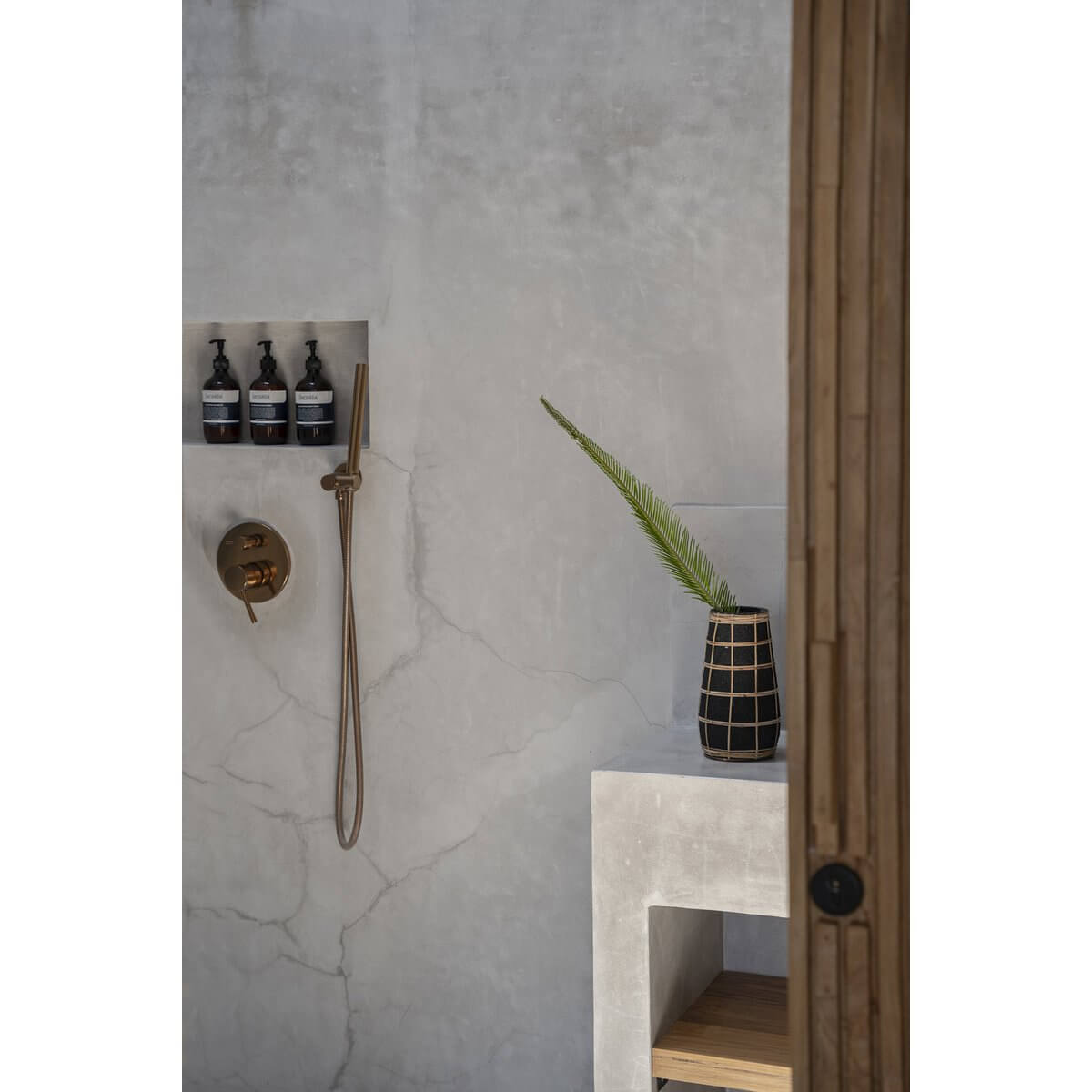 The Cutie Vase - Zwart Naturel - M in a minimalist bathroom setting with raffia detail and decor elements.