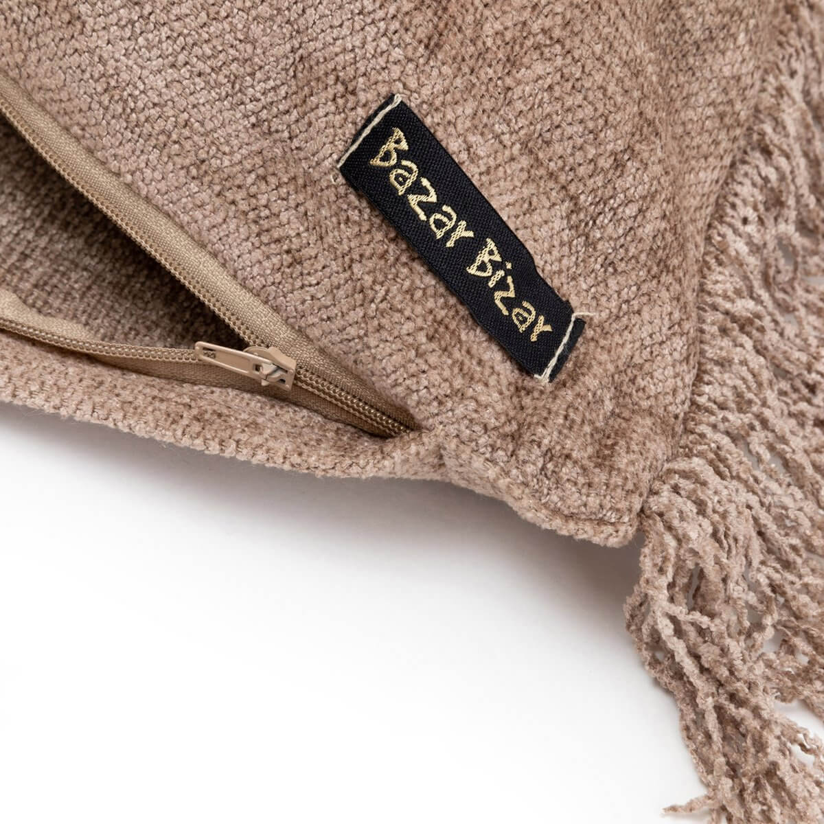 Close-up of a textured cushion cover with a zipper and fringe detail, labelled Bazar Bizar.